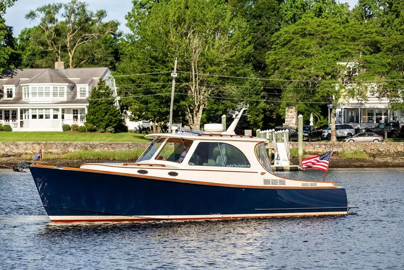 Slide: The Image of Hinckley Picnic Boat Mark III 2011 cruising on a serene river near elegant waterfront homes. - 12