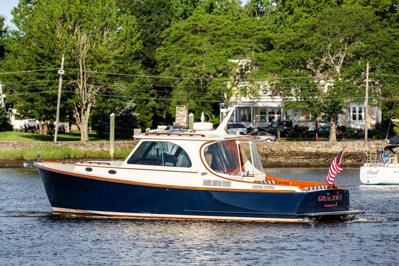 Slide: The Image of 2011 Hinckley Picnic Boat Mark III cruising on a scenic river with lush greenery. - 14