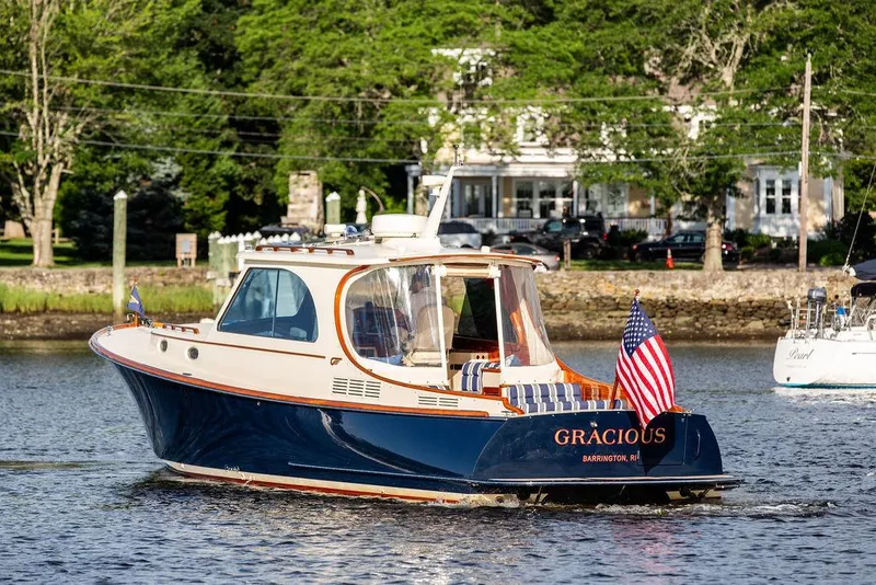 Slide: The Image of 2011 Hinckley Picnic Boat Mark III cruising on a scenic river with American flag. - 16