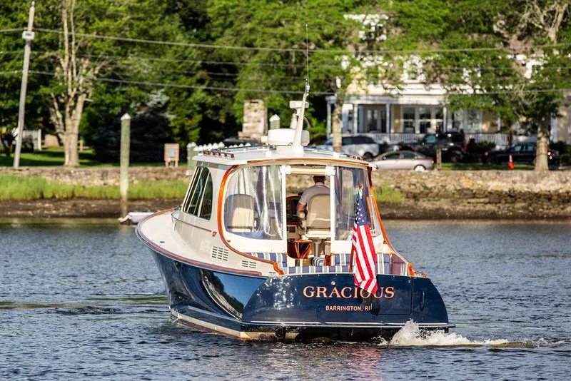 Slide: The Image of Hinckley Picnic Boat Mark III, 2011, cruising on a serene river with American flag. - 19