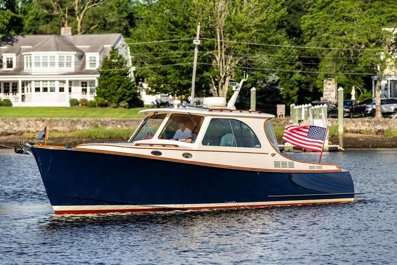 Slide: The Image of 2011 Hinckley Picnic Boat Mark III cruising on a scenic river with American flag. - 2