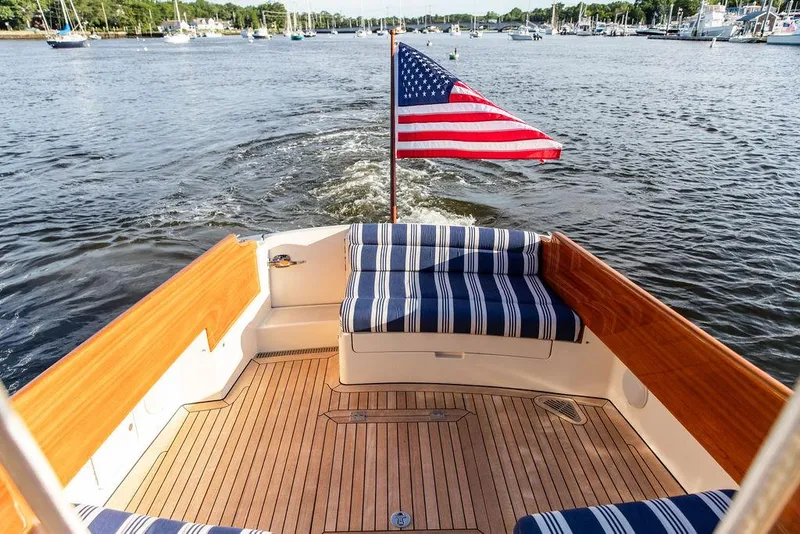 Slide: The Image of Hinckley Picnic Boat Mark III 2011 with American flag, cruising on a scenic waterway. - 31
