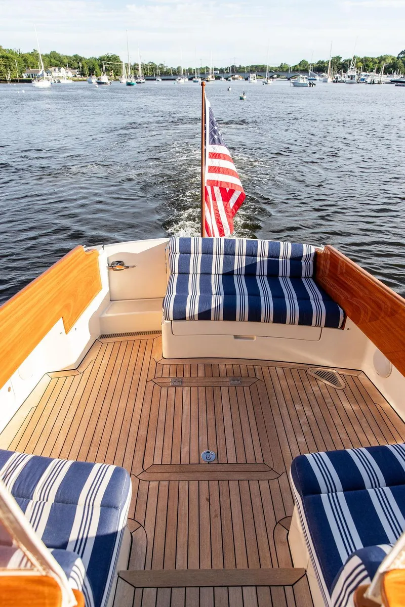 Slide: The Image of Hinckley Picnic Boat Mark III 2011 with striped seating, cruising on a scenic lake. - 33