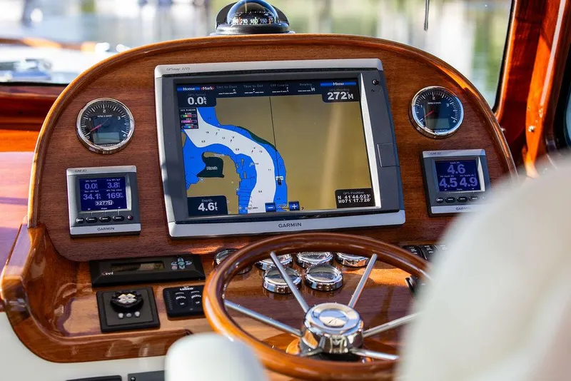 Slide: The Image of Hinckley Picnic Boat Mark III 2011 dashboard with Garmin navigation system and wooden steering wheel. - 48