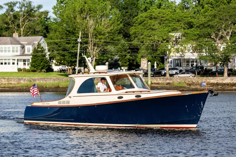 Slide: The Image of 2011 Hinckley Picnic Boat Mark III cruising on a scenic river with lush greenery. - 7