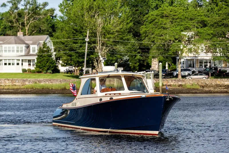 Slide: The Image of 2011 Hinckley Picnic Boat Mark III cruising on a scenic river near waterfront homes. - 9