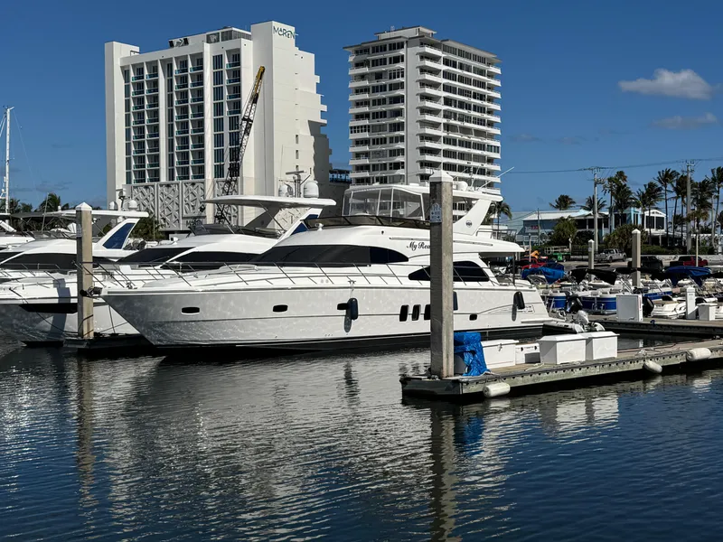 Slide: The Image of Luxury 2012 Neptunus 62 Flybridge yacht docked in a marina, with modern buildings nearby. - 7