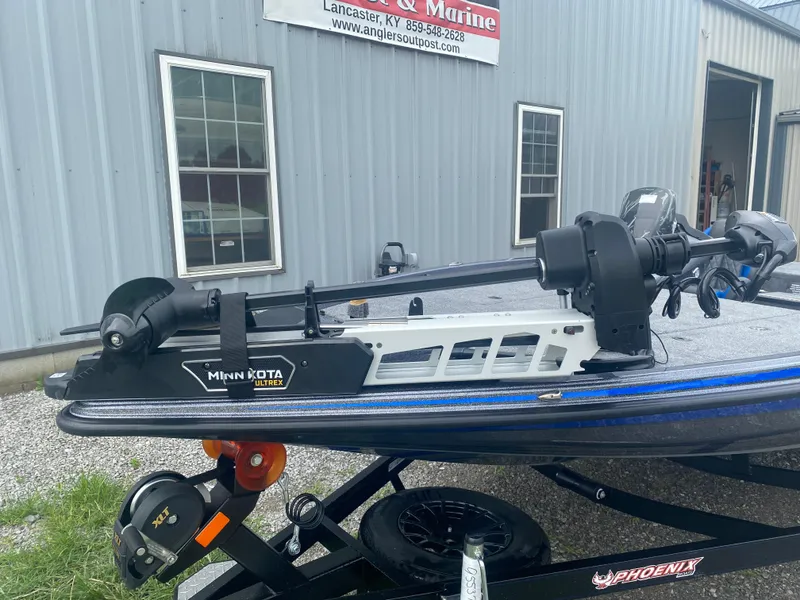 Slide: The Image of 2026 Phoenix 721 ZXL boat with Minn Kota Ultrex motor, parked outside a marine shop. - 4