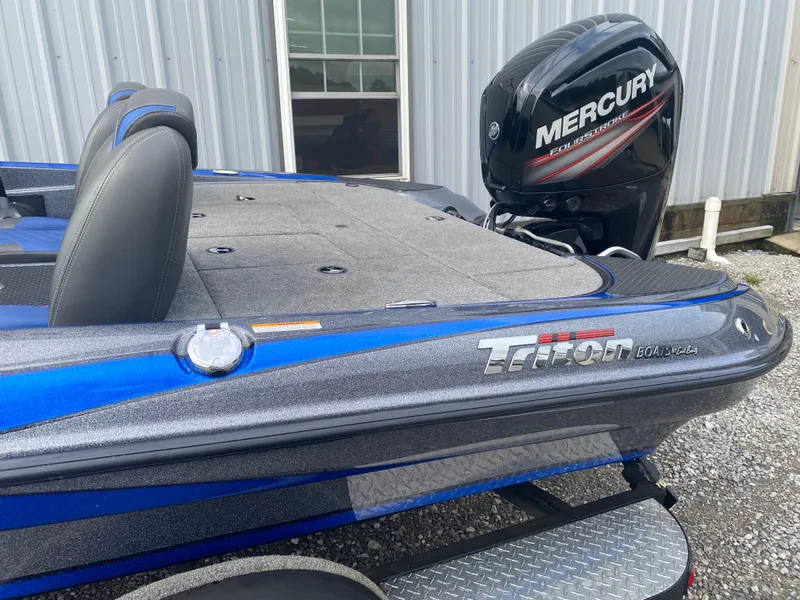 Slide: The Image of 2017 Triton 179 TrX boat with Mercury FourStroke engine, parked near a metal building. - 7