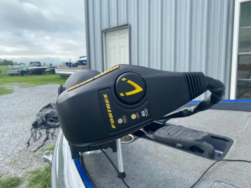 Slide: The Image of Triton 179 TrX 2017 boat with Fortrex trolling motor, parked near a metal building. - 9