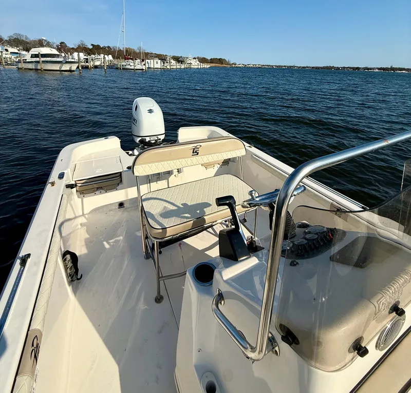 Slide: The Image of 2023 Carolina Skiff 21 LS boat on calm water, featuring a spacious deck and motor. - 5