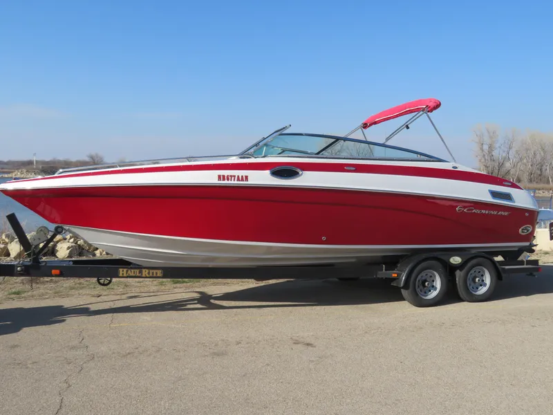 Slide: The Image of 2012 Crownline 275 SS boat in red on a trailer, parked outdoors. - 2