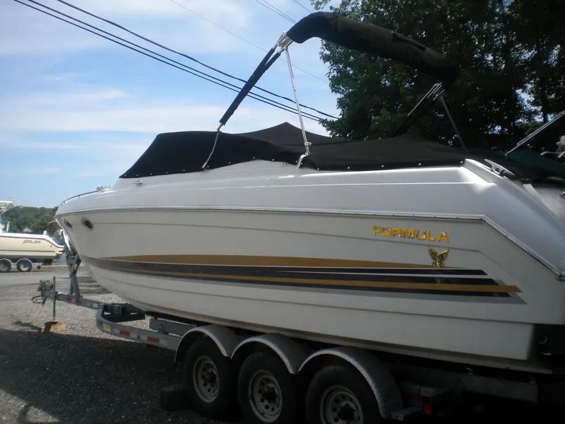 Slide: The Image of 2002 Formula 330 SS boat on trailer, covered and parked outdoors. - 2