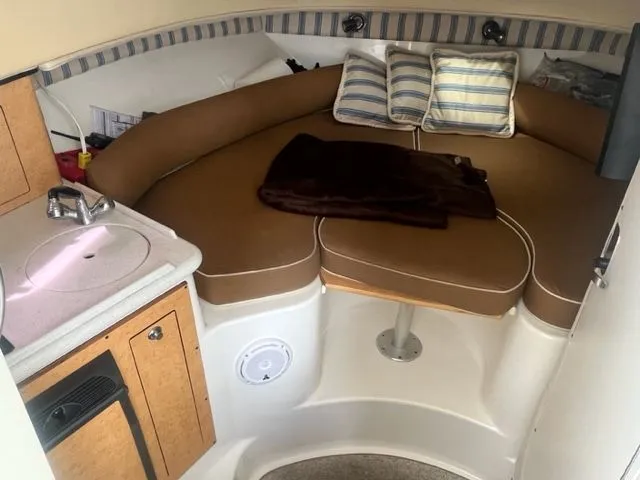 Slide: The Image of 2008 Edgewater 265 Express cabin with cozy seating, striped pillows, and compact kitchenette. - 10