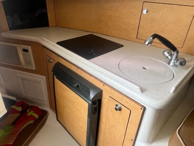 Slide: The Image of 2008 Edgewater 265 Express boat kitchenette with sink, stove, and microwave. - 11