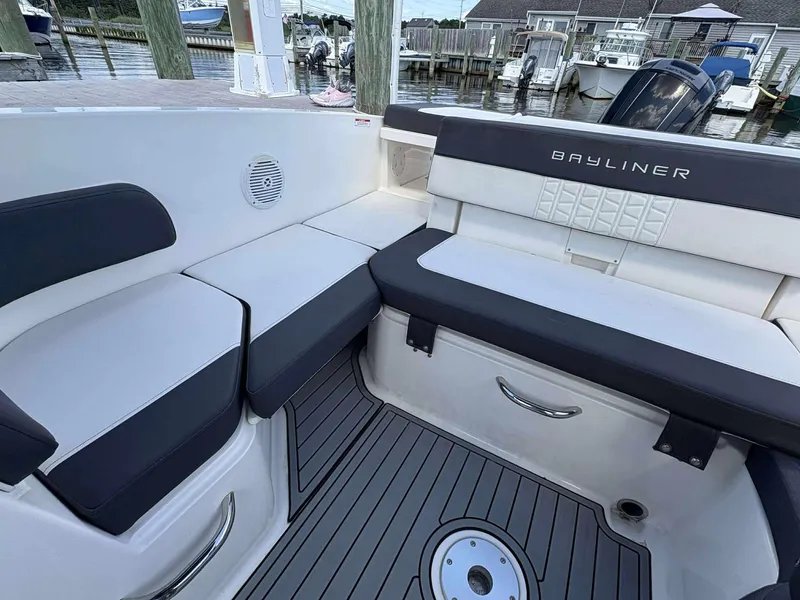 Slide: The Image of 2019 Bayliner VR6 boat interior with cushioned seating and sleek design at a marina. - 11
