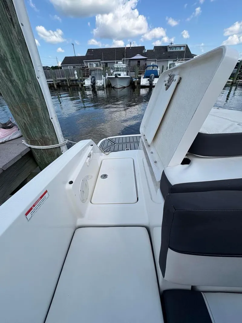 Slide: The Image of 2019 Bayliner VR6 boat interior with open storage, docked at marina under blue sky. - 14