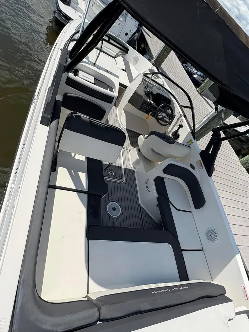 Slide: The Image of 2019 Bayliner VR6 boat interior with seating, steering wheel, and canopy, docked by the water. - 6