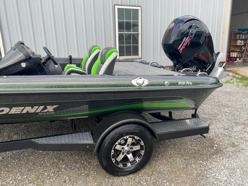 Slide: The Image of 2025 Phoenix 818 Pro boat with green accents and Mercury engine, parked on gravel. - 5