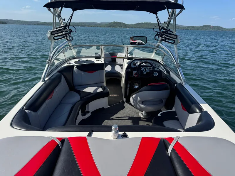 Slide: The Image of 2006 Tigé 22V boat interior with seating, steering wheel, and speakers on a lake. - 10