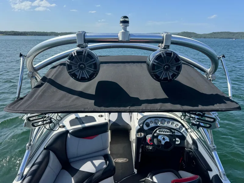 Slide: The Image of 2006 Tigé 22V boat interior with speakers and canopy on a sunny lake. - 11
