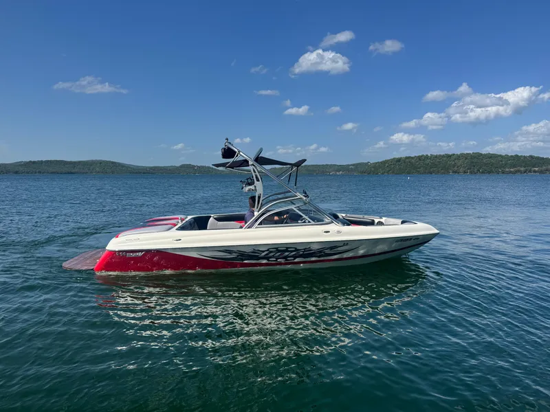 Slide: The Image of 2006 Tigé 22V boat on a calm lake under a clear blue sky. - 3