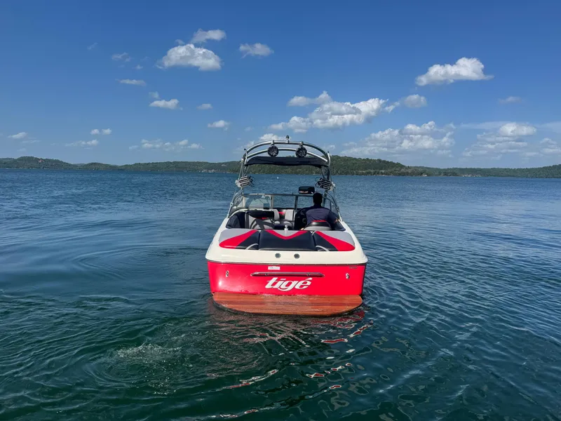 Slide: The Image of 2006 Tigé 22V boat on a calm lake under a clear blue sky. - 4