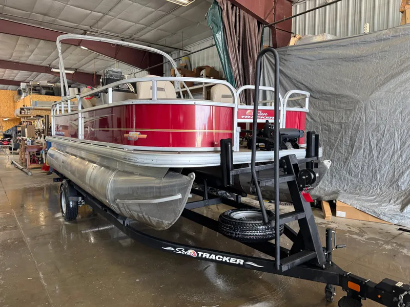 Slide: The Image of 2023 Sun Tracker Bass Buggy 18 DLX pontoon boat on trailer in a garage. - 2