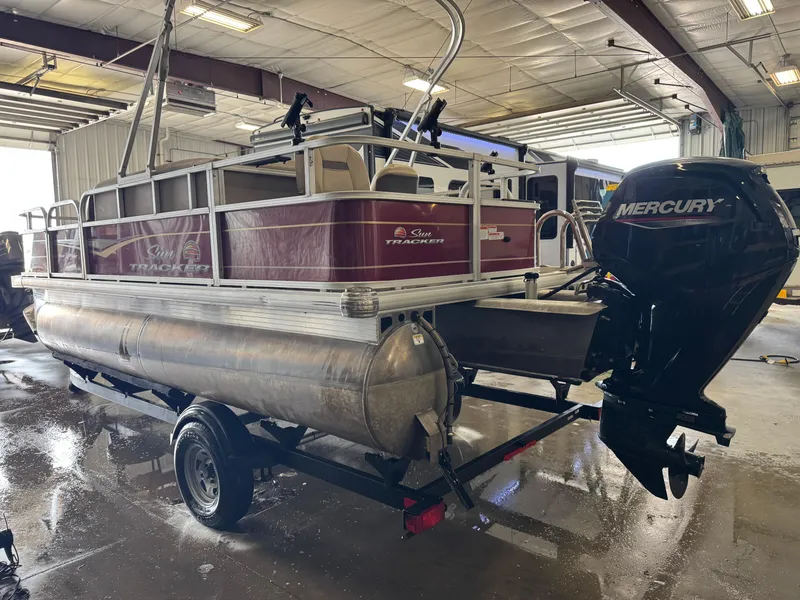 Slide: The Image of 2023 Sun Tracker Bass Buggy 18 DLX pontoon boat with Mercury outboard motor in a garage. - 4
