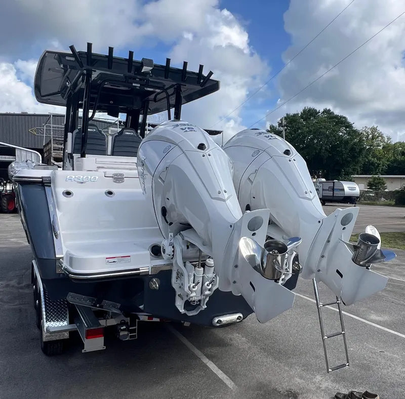 Slide: The Image of 2025 Robalo R300 Center Console boat with dual outboard engines, parked outdoors. - 11