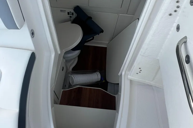 Slide: The Image of Interior of 2025 Robalo R300 Center Console boat, featuring compact bathroom amenities. - 19