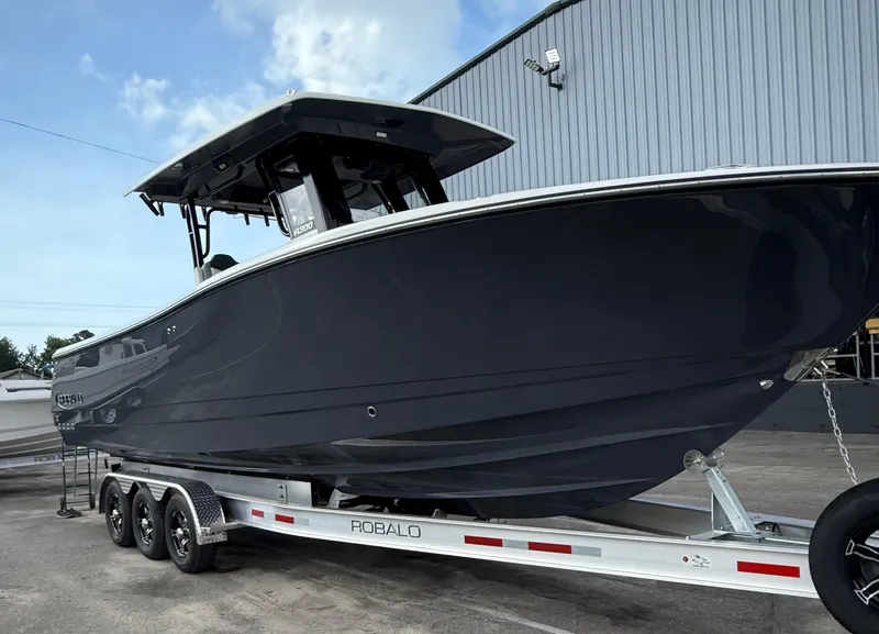 Slide: The Image of 2025 Robalo R300 Center Console boat on trailer, parked outdoors. - 3