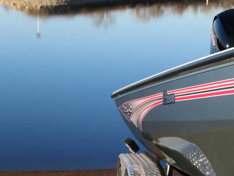 Slide: The Image of 2024 Ranger RB200 boat by a calm lake, showcasing sleek design and vibrant stripes. - 16