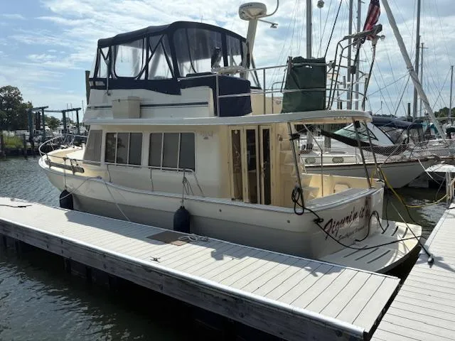 Slide: The Image of 2006 Mainship 400 Trawler docked at marina, featuring upper deck and enclosed cabin. - 1