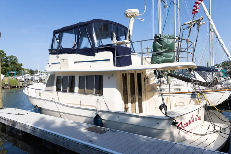 Slide: The Image of 2006 Mainship 400 Trawler docked at marina, featuring blue canopy and American flag. - 14