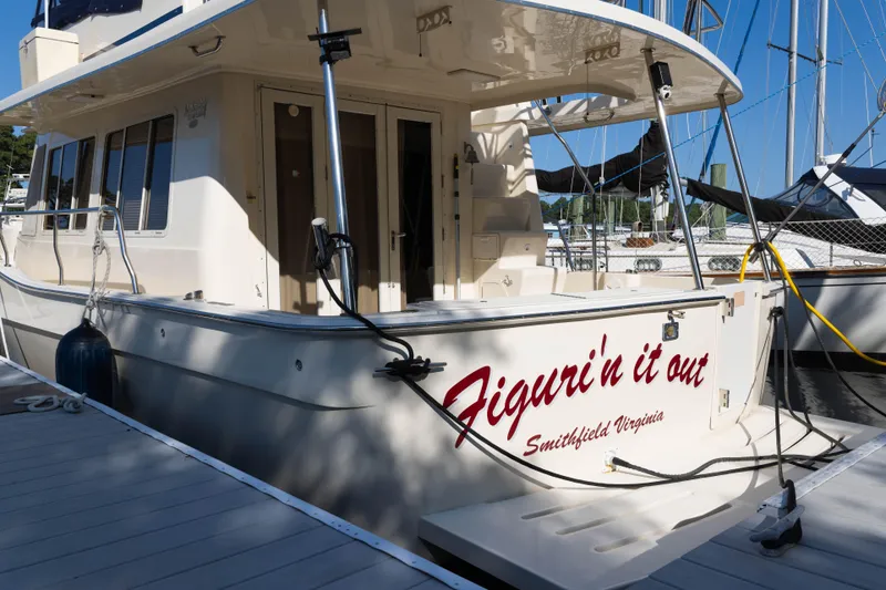Slide: The Image of 2006 Mainship 400 Trawler docked, featuring "Figuri'n it out" text on the stern. - 15