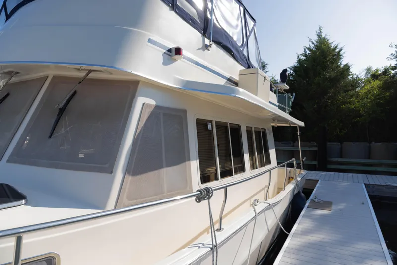Slide: The Image of 2006 Mainship 400 Trawler docked, showcasing sleek design and spacious windows. - 20