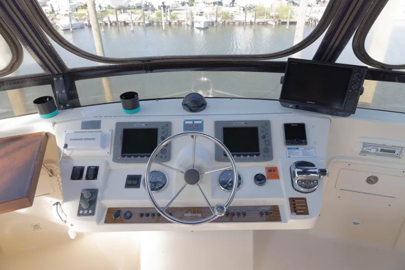 Slide: The Image of 2006 Mainship 400 Trawler helm with navigation equipment and steering wheel, overlooking marina. - 27