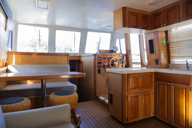 Slide: The Image of 2006 Mainship 400 Trawler interior with wooden cabinetry, dining area, and helm station. - 44