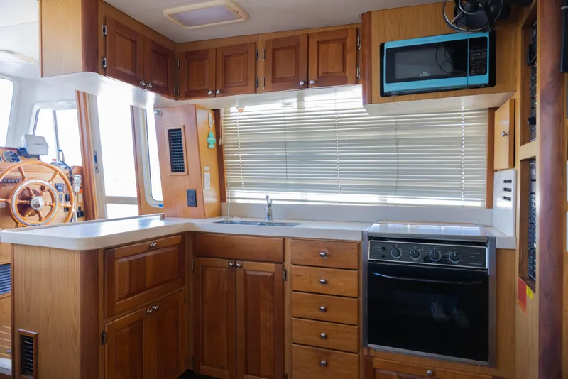 Slide: The Image of 2006 Mainship 400 Trawler kitchen with wooden cabinets, stove, and microwave. - 46