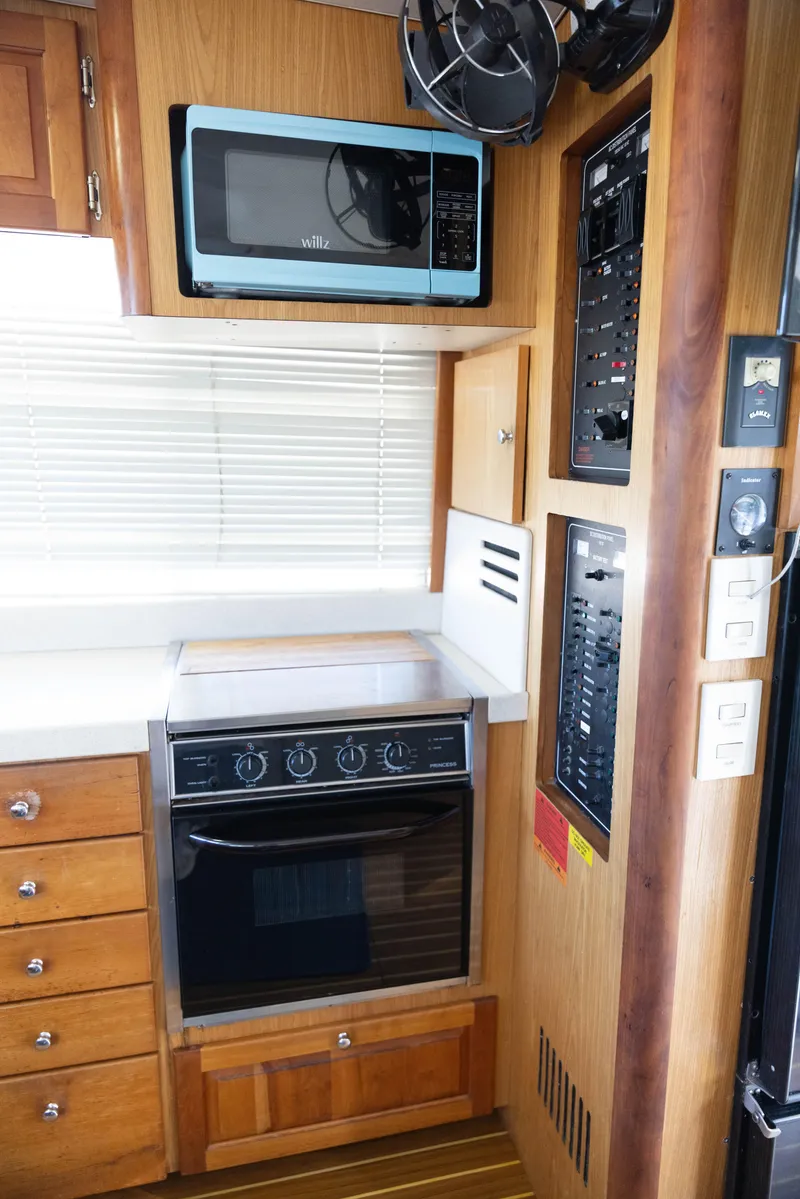 Slide: The Image of 2006 Mainship 400 Trawler kitchen with oven, microwave, and control panels. - 49