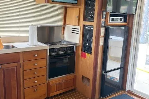 Slide: The Image of 2006 Mainship 400 Trawler kitchen with stove, fridge, and wooden cabinetry. - 8