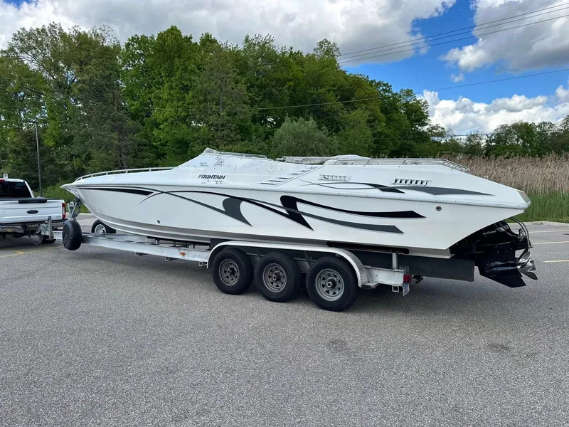 Slide: The Image of 1994 Fountain 35 Lightning boat on trailer, parked outdoors with trees and cloudy sky. - 3