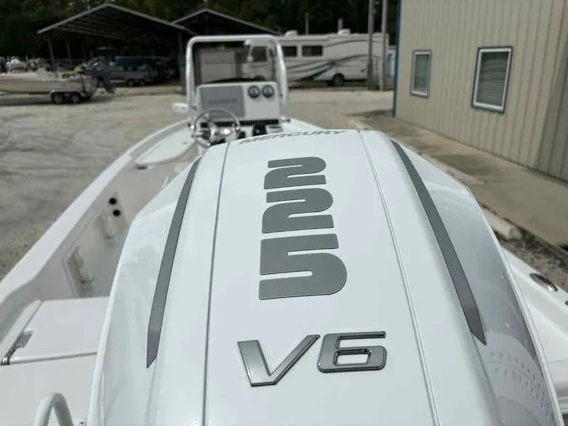 Slide: The Image of 2026 Blazer PureBay 2200 boat with Mercury 225 V6 engine, parked outdoors. - 18