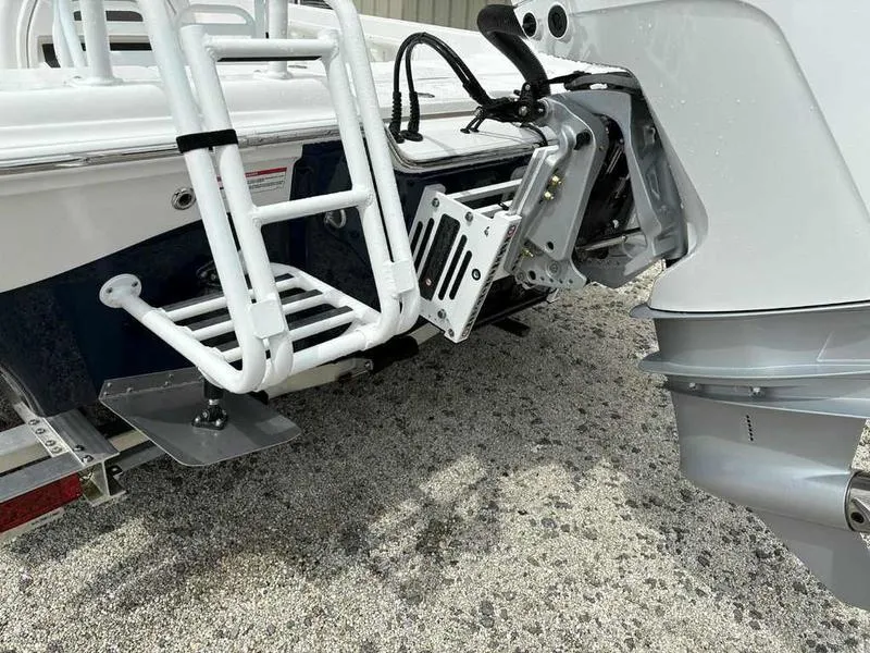 Slide: The Image of 2026 Blazer PureBay 2200 boat stern with motor and ladder on gravel surface. - 26