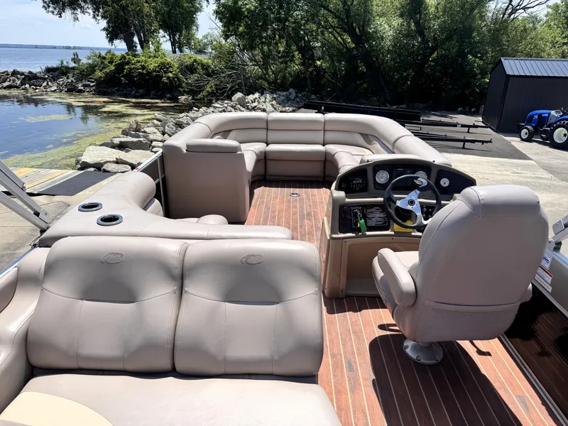 Slide: The Image of 2013 Crest Classic 230SLR pontoon boat with spacious seating and modern dashboard, docked by a scenic shoreline. - 6
