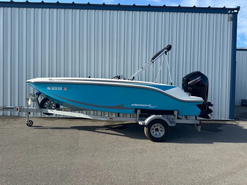 The Image of 2022 Bayliner Element M17 boat on trailer, parked by a metal building. - 0