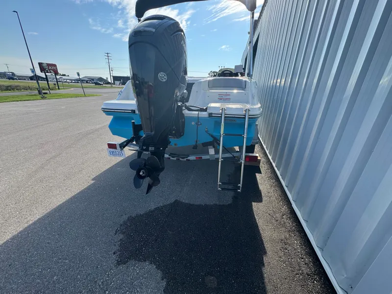 Slide: The Image of 2022 Bayliner Element M17 boat with outboard motor and ladder, parked near a building. - 16