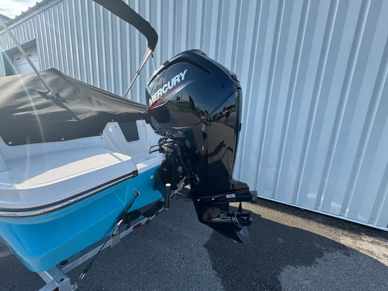 Slide: The Image of 2022 Bayliner Element M17 boat with Mercury outboard motor, parked near a corrugated metal wall. - 17