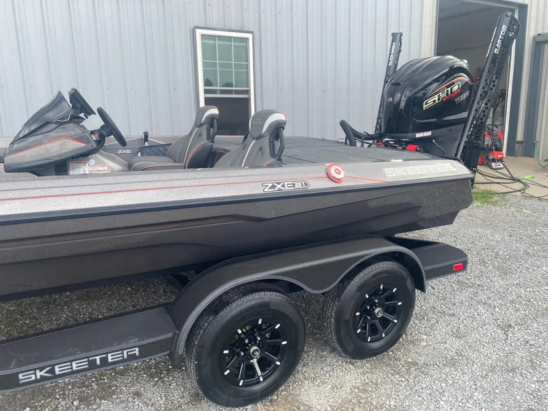 Slide: The Image of 2026 Skeeter ZXE 21 boat with Yamaha engine, parked on gravel near a metal building. - 6